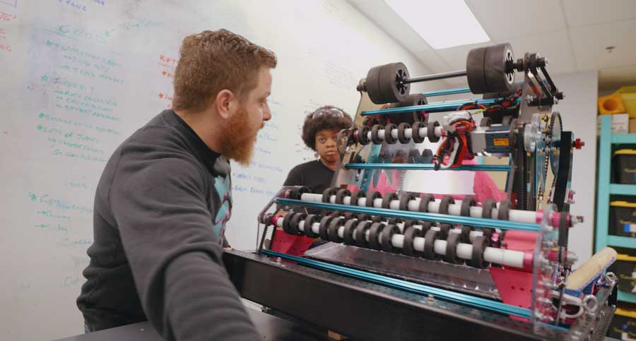 Student and mentor working on robot
